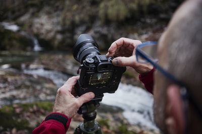 男子使用数码单反相机拍摄河流照片